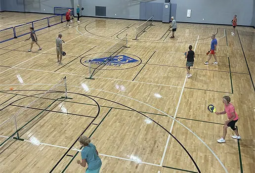 Athletes playing pickleball on gym court